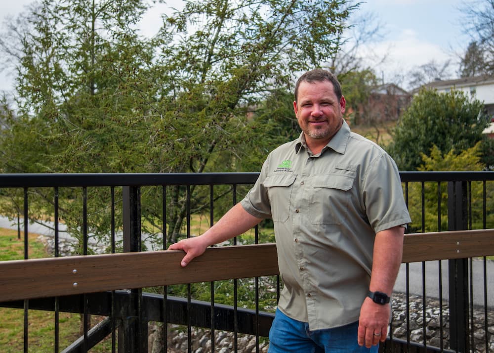 Josh, cofounder of HisGround LLC, standing outdoors on a bridge in Maryville, Tennessee.