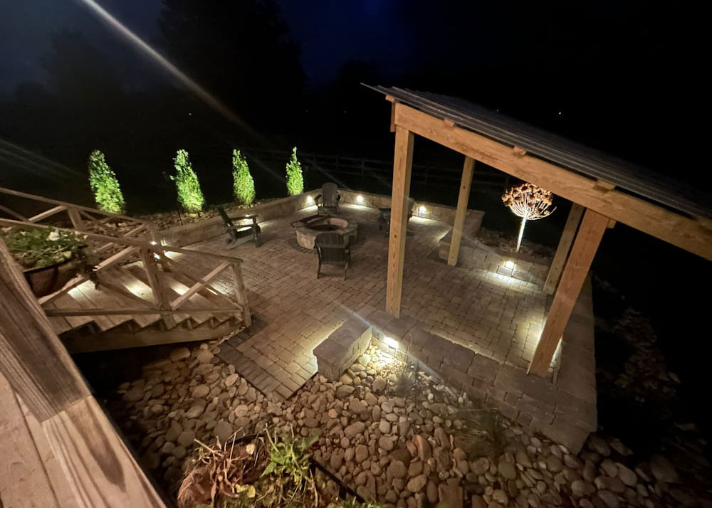 Outdoor patio with ledge lighting and uplighting illuminating stone hardscape at night